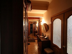 круглое зеркало над тумбочкой, мягкий пуфик, шкаф-купе в бежевом коридоре сталинской квартиры