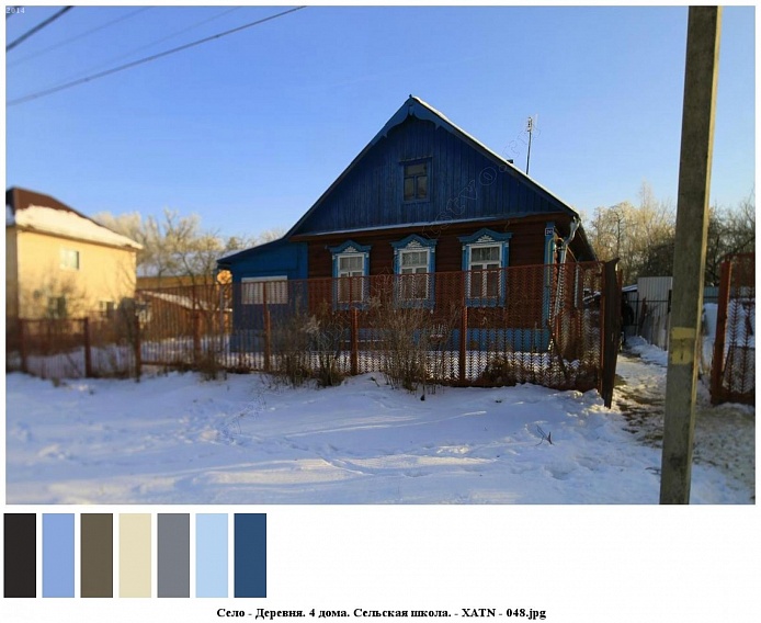 небольшой ухоженный жилой деревянный дом в сине-коричневом цвете на заснеженном участке за сетчатым забором на селе
