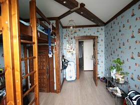 голубые обои с рисунком на стенах детской комнаты с деревянной балкой на потолке простой семейной квартиры