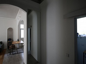 деревянный стол, стул и круглая подставка для цветов в нише гостиной скандинавской квартиры из арочного дверного проема длинного белого коридора