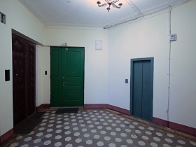 темно серая дверь лифта на этаже жилого дома с входными дверьми квартир на просторной лестничной площадке