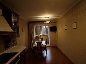 картины на бежевых стенах,телевизор в углу кухни, совмещенной с лоджией трехкомнатной современной квартиры с детской