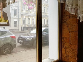 припаркованные машины у бардюра пешеходной дорожки через стекла пластиковых окон классической рюмочной, бутербродной, закусочной СССР