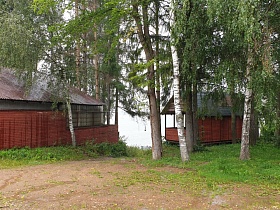 ряды деревянных домиков с треугольной крышей на самом краю речки в окружении высоких сосен и стройных белых берез
