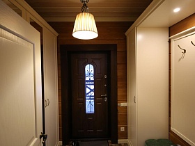 бежевая прихожая и шкаф купе с зеркальными дверцами у входной коричневой двери в деревянном съемном коттедже