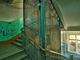лестница с зелеными перилами у стены с окрашенными зелеными панелями