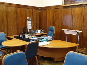 синее кожаное высокое кресло у полукруглого стола с монитором, телефоном, ксероксом и офисной техникой на поверхности в углу кабинета Министра СССР для съемок кино