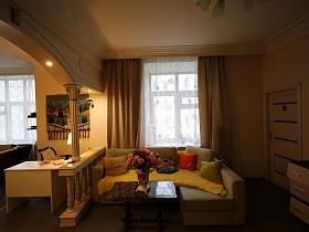 полированый журнальный столик и мягкий угловой диван у окна гостиной