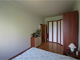 длинный угловой шкаф с белыми дверцами в спальной комнате простой квартиры на Садовом