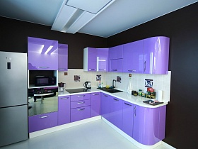 двухкамерный серебристый холодильник, фиолетовая мебельная стенка у коричневой стены кухни с люстрой в стиле хай-тек на белом потолке молодежной квартиры