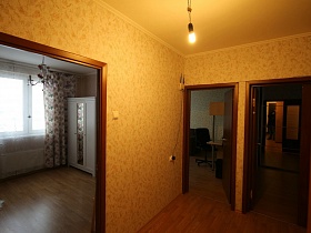 открытые двери в разные комнаты из длинного коридора большой трехкомнатной квартиры после переезда