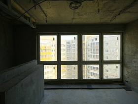 бетонные плиты на полу комнаты недостроенного пентхайса молодежи с панорамными окнами и многочисленными проводами на потолке