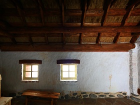 пол и фундамент выложены диким камнем в домике с побеленными стенами и высоким потолком на территории ресторана, стилизованного под хутор