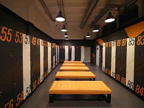  ораньжевые банкетки и элементы геометрических фигур ораньжевого цвета на стенах современной спортивной  раздевалки