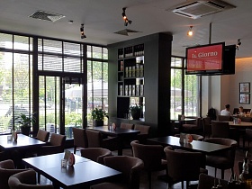 коричневые кресла с полукруглыми спинками у коричневых столиков в просторном зале ресторана с большими окнами на всю стену