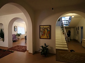 небольшие ковры на полу в разных комнатах с арочным переходом гостевого двухэтажного дома с придорожным кафе