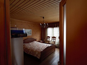 большая деревянная кровать с белым покрывалом и стулями у окна