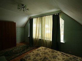шкаф для одежды, зеленая дорожка до окна с зелеными шторами в зеленой спальне второго этажа съемного дома в сосновом лесу