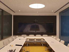 ДВа больших телевизора в переговорной комнате из стекла