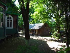 деревянная постройка с шифером на крыше у забора  на ухоженном участке деревянной художественной дачи-музей эпохи СССР