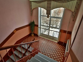 красивая лестничная площадка с коричневой плиткой на полу и с панелями на стене в типовой школе