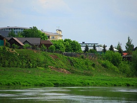 жилой комплекс на крутом берегу красивой реки в окружении зелени