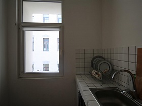 соседние окна дома из небольшого окна светлой кухни зонированной комнаты современной скандинавской квартиры