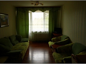 диван, кресла, подушки, шторы и обои зеленого цвета в комнате отдыха номера