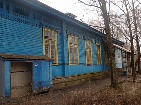 голубое деревянное одноэтажное здание больницы под крышей с решетками на окнах, козырьком над крыльцом у перекрытых входных дверей