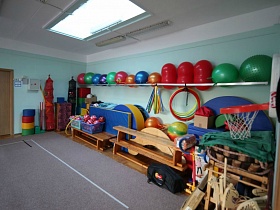 красочный разноцветный спортивный инвентарь у стены спортзала детского сада