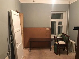 белые дверные полотна, коричневый полированный стол у листа крагиса, деревянные стулья с зеленой обивкой у окна комнаты с серыми стенами квартиры N6 на Остоженке