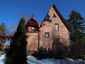 торец двухэтажного загородного дома с треугольной крышей, небольшими окнами в стене и башней для съемок кино