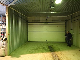 большие ворота просторного гаража с зелеными стенами загородного дома