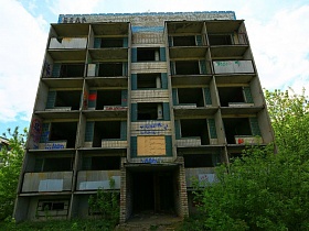 фасад многоэтажного заброшенного дома без окон, балконных плит  в областном квартале
