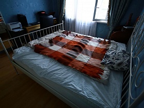 клетчатый цветной плед на белой большой кровати с металлическими спинками в голубой спальне актерской трехкомнатной квартиры