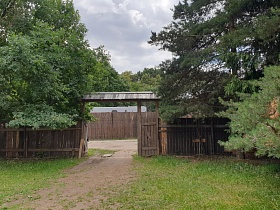 деревянный дощатый забор с большими воротами под треугольной крышей большого двора с деревянными постройками в деревне для съемок кино
