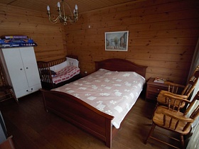 рядом с кроватью стоит детская кроватка и белый шкаф для одежды