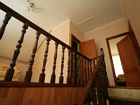 просторный холл второго этажа над лестницей с открытыми дверьми в комнаты пустого съемного дома в сосновом лесу