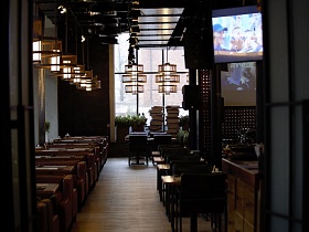 столики с мягкими диванами у окон, и квадратные столики со стульями у сцены в светлом здании уютного крафтового ресторана