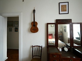 гитара на стене над стулом в спальной комнате