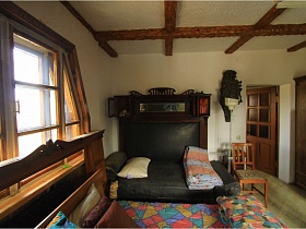 стул и торшер у темной кровати с подушкой и сложенным одеялом в спальной комнате с белыми стенами