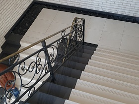 черная под мрамор плитка у стены лестничной площадки современного стильного подъезда жилого дома