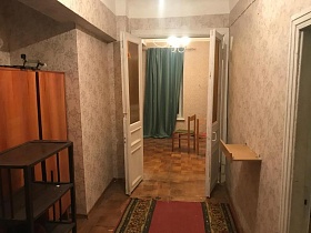 коричневая этажерка у шкафа для одежды в нише прихожей с цветочными бежевыми обоями и красной дорожкой на полу квартиры N6 на ул.Остоженка