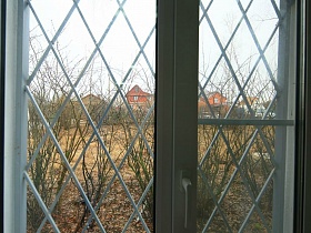 вид из окна с решеткой сельского клуба на двухэтажные кирпичные дома напротив в Подмосковье