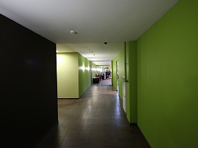 яркое освещение настенных бра в уютном холле фитнес клуба с салатовыми стенами и квадратной плиткой на полу