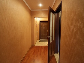 небольшой коврик на полу со светлой плиткой у коричневой входной двери в прихожей квартиры государственного служащего