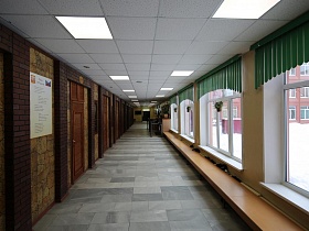 длинный школьный коридор школы с белым потолком и серой плиткой на полу
