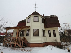 компактная современная двухэтажная загородная дача с деревянным крыльцом под навесом