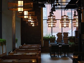необычные оригинальные круглые подвесные светильнике на потолке стильного и уютного крафтового ресторана над индивидуальными столиками