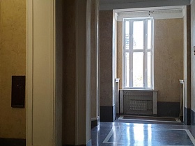 закрытые двери лифтовой кабины на первом этаже красивого классического подъезда высотного жилого дома сталинки